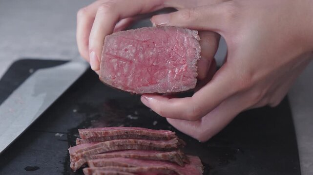 ローストビーフのブロック肉を両手で持ち、柔らかさとピンク色の断面をアピールする手元