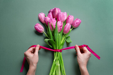 Woman hands tying pink ribbon on tulips, Mother's Day
