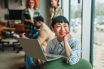 Fototapeta premium Businesswoman working on laptop in modern office thinking about future