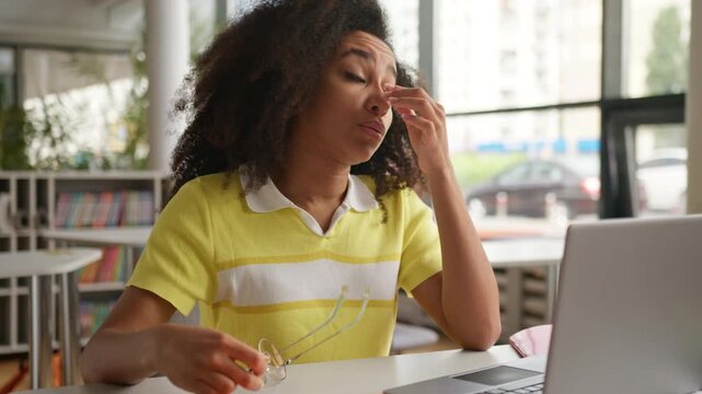 Exhausted overload African American woman girl student take off glasses feeling pain discomfort headache studying with laptop overworked female with computer feel ache blurry eyesight eyes irritation