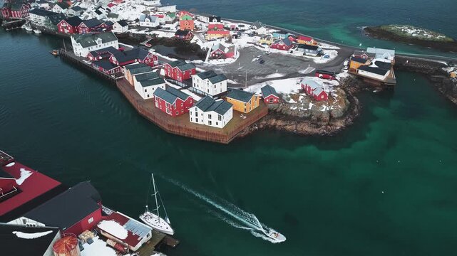 Aerial view of colorful buildings and turquoise waters create a striking contrast with the snow-covered landscape, Henningsv&aelig;r, Nordland, Norway.