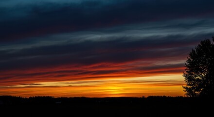 Fototapeta premium A dramatic and colorful sunset fills the sky, contrasting sharply with the stark, deep black silhouettes of the distant landscape and trees at twilight ,tranquil ,abstract ,beautiful