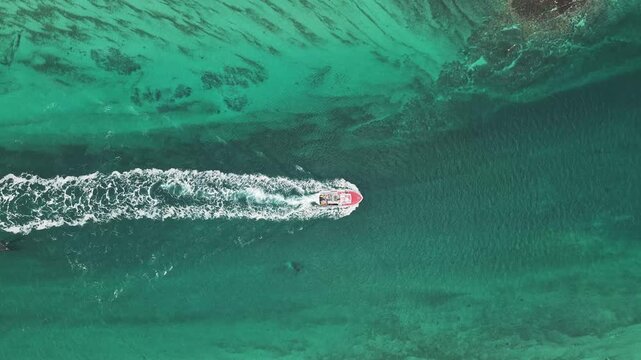 Aerial view of the rugged coastline where the turquoise sea meets the snow-dusted earth, punctuated by a small red structure, M&oslash;lnarodden, Nordland, Norway.