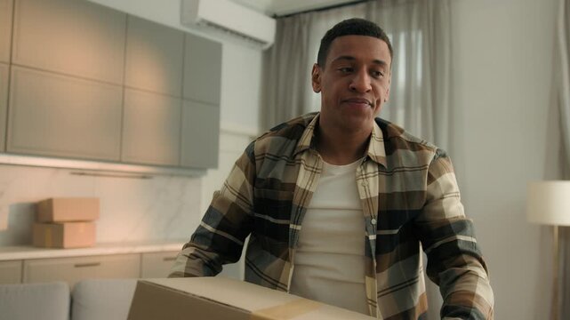 Clumsy African American man carry heavy parcels drop boxes irritated frustrated angry fatigue with relocation moving in new home male guy renting flat receiving shopping delivery packages falling