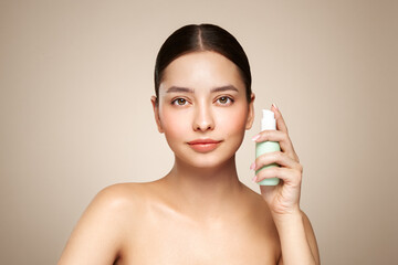 Beautiful woman with bottle of moisturizer cream. Photo of woman with perfect skin on beige background. Beauty and Skin care concept