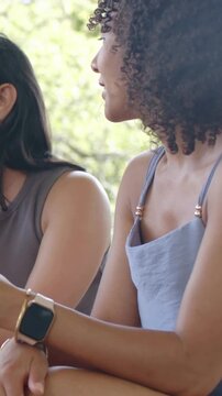 Vertical video: Arriving drink, woman chatting while friend listening on patio, watch on wrist