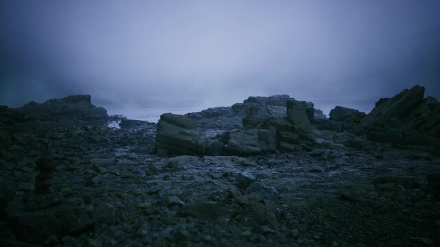 pebble beach under heavy predawn sky, scattered boulders and low surf, mist hugging shoreline with muted blue cast, serene lonely coastal mood