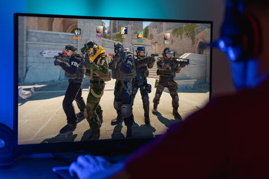Gamer sitting in front of a computer monitor with Counter-Strike 2 logo on screen, esports fan ready to play tactical first-person shooter video game.