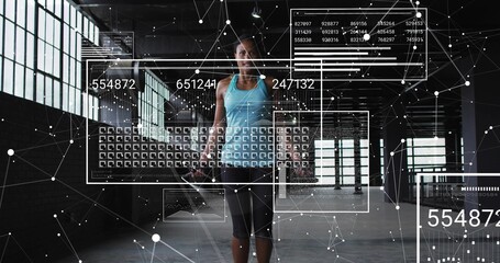 Standing woman wearing turquoise tank lifting handheld weight at warehouse gym, showing AR overlays © vectorfusionart