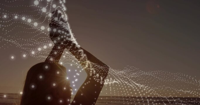 Silhouette woman raising hands, sun aligning at head, animating dotted wave showing tech data flow