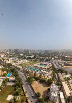Aerial view of the urban landscape featuring the St. Patrick's Cathedral area with school buildings, a sports field, and busy streets under a clear sky in Karachi, Sindh, Pakistan.