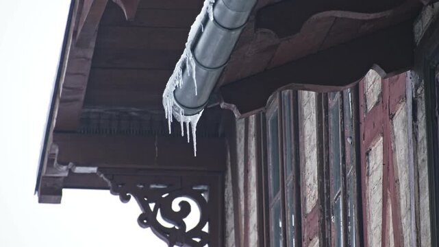 Massive Long Dangerous Icicle Hanging from Frozen Rain Gutter Posing Injury Hazard for Pedestrians