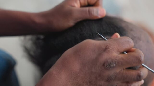 Closeup comb sectioning natural hair, skilled stylist prepping textured hair for braid with precise parting and controlled tension, tail comb and clips used for neat rows, concentrated hands