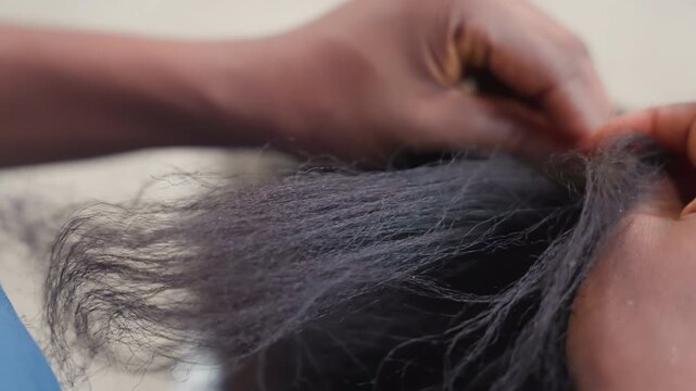 Closeup black hands detangling hair, gentle fingers separating textured strands in calm home setting, patient grooming ritual focused on roots and scalp, soft natural light, intimate atmosphere