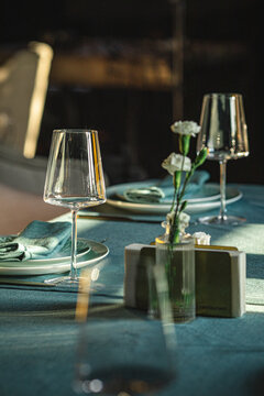 Stylish table setting with wine glasses plates napkins and flowers in soft warm restaurant lighting