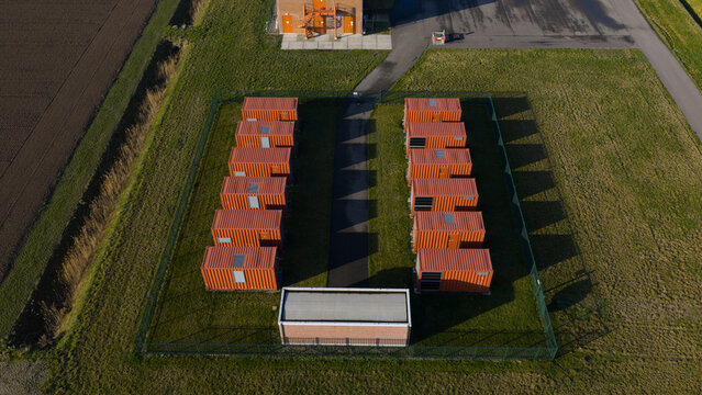 Aerial view of Haringvliet Zuid Energy Park showing rows of orange battery storage containers in a fenced area Middelharnis, Netherlands.