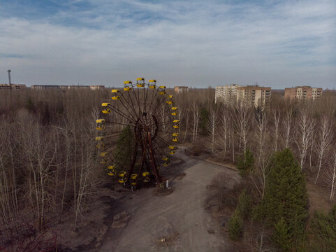 Aerial view of the abandoned Ferris wheel with yellow cabins surrounded by leafless trees and derelict buildings in Pryp'yat', Kyiv Oblast, Ukraine.