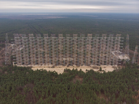 Aerial view of the massive Duga radar station surrounded by dense pine forest under an overcast sky in Prypyat, Kyiv Oblast, Ukraine.