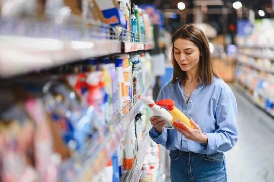 Woman choosing cleaning products at supermarket aisle