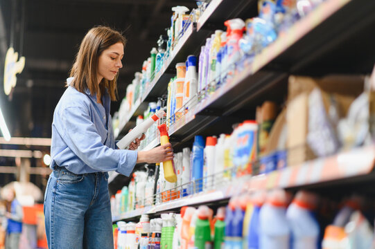Woman shopping for cleaning supplies in supermarket aisle