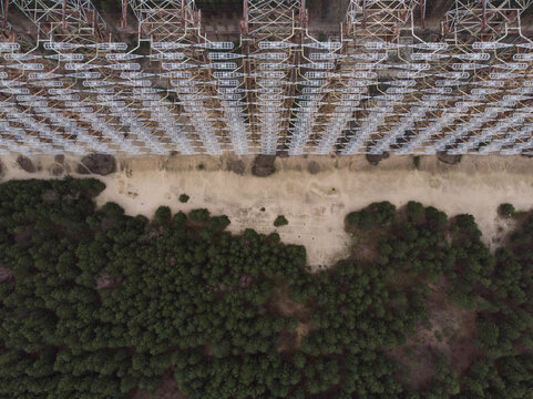 Aerial view of the massive Duga radar station lattice structure bordering a dense pine forest in Prypyat, Kyiv Oblast, Ukraine.
