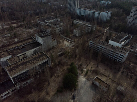 Aerial view of abandoned apartment blocks and decaying concrete structures surrounded by leafless trees in Pripyat, Kyiv Oblast, Ukraine.