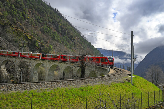 Swiss mountain train Bernina Express, circular viaduct at Brusio. Railway line for express is the highest railway in Europe, UNESCO World Heritage Site. One of the most spectacular ways to cross Alps