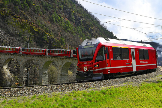 Swiss mountain train Bernina Express, circular viaduct at Brusio. Railway line for express is the highest railway in Europe, UNESCO World Heritage Site. One of the most spectacular ways to cross Alps
