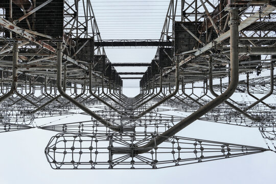 Aerial view of the massive steel lattice structure of the Duga radar system with intricate metal grids and pipes under an overcast sky in Prypyat, Kyiv Oblast, Ukraine.