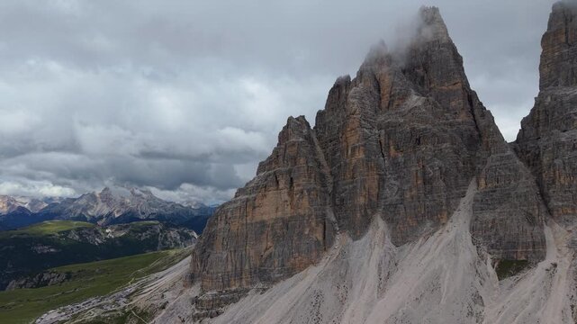 Stunning aerial perspective of the Tre Cime di Lavaredo in the Dolomites, revealing the rugged peaks and green valleys under a cloudy sky