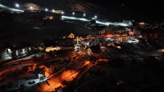 Night Drone view of Gudauri in Georgia town with snow covered mountains, ski slopes and town after fresh snowfall in winter season. Gudauri ski resort with fresh powder snow, Georgia.