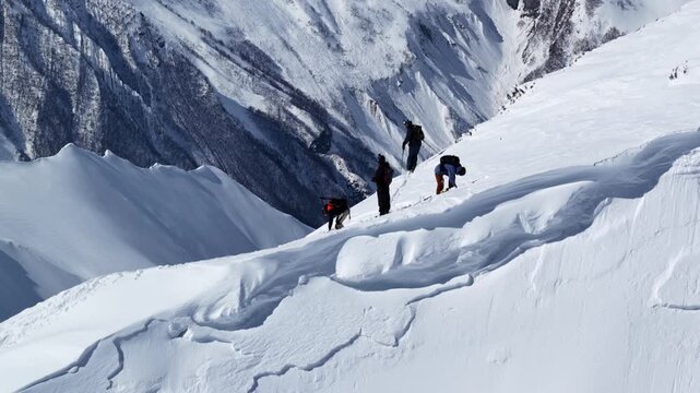 Freeride skiers climbing and descending Bidara peak in Gudauri on deep fresh powder snow, winter adventure in Georgia mountains. Backcountry freeride and skiing untouched powder in snowy mountains.