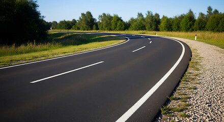 Obraz premium Winding asphalt road through a lush green countryside landscape