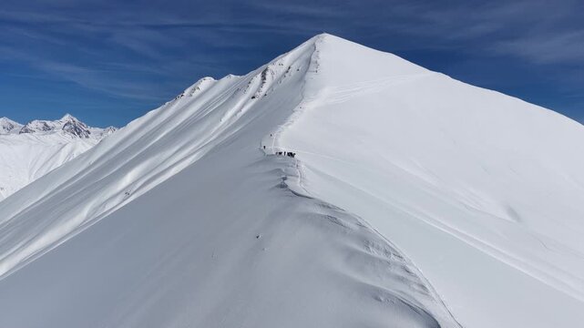 Freeride skiers climbing and descending Bidara peak in Gudauri on deep fresh powder snow, winter adventure in Georgia mountains. Backcountry freeride and skiing untouched powder in snowy mountains.