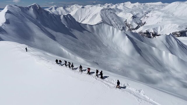 Freeride skiers climbing and descending Bidara peak in Gudauri on deep fresh powder snow, winter adventure in Georgia mountains. Backcountry freeride and skiing untouched powder in snowy mountains.
