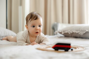 Fototapeta premium Captivating Baby Boy Plays with a Toy Train on a Bed, Displaying Early Childhood Joy