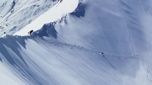 Freeride skiers climbing and descending Bidara peak in Gudauri on deep fresh powder snow, winter adventure in Georgia mountains. Backcountry freeride and skiing untouched powder in snowy mountains.