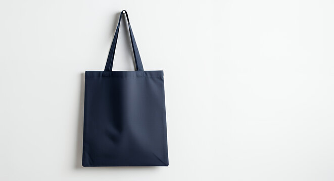 Plain navy blue canvas tote bag hangs on simple white wall eco-friendly reusable fabric carry bag features minimalist design ready for branding perfect for shopping school daily use versatile tote bag