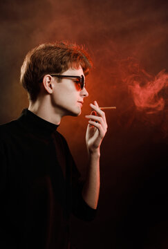 Cinematic side profile of male model with sunglasses and cigarette smoke.
