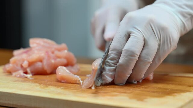 Close up of cutting raw chicken on wooden board, food preparation process, cooking, kitchen hygiene and fresh ingredients