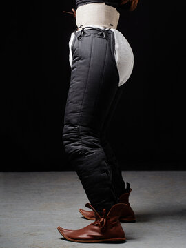 Black padded HEMA pants with white lining and brown medieval shoes in side pose.