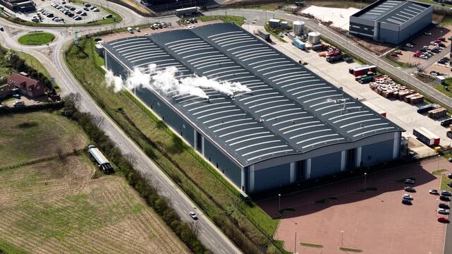 Aerial view of a large industrial building emitting white smoke, contrasting against the surrounding green fields, Doncaster, England, United Kingdom.