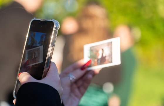 a girl takes a photo of a printed photo on her phone