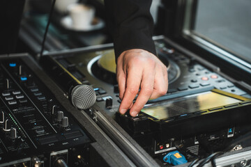 Close up of man artist DJ mixing and scratching music mixer controller. Attractive male musician DJ having fun mixing music on console touching buttons and playing electronic music at neon party © aifeati