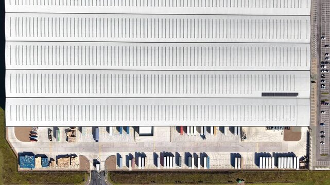 Aerial view of a vast industrial building with a long row of loading bays and a parking lot full of cars, Doncaster, England, United Kingdom.