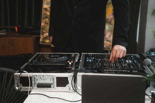 Close up of man artist DJ mixing and scratching music mixer controller. Attractive male musician DJ having fun mixing music on console touching buttons and playing electronic music at neon party