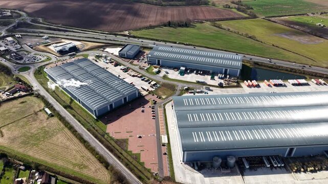 Aerial view of large industrial buildings with silver roofs and surrounding green fields, creating a contrast, Doncaster, England, United Kingdom.