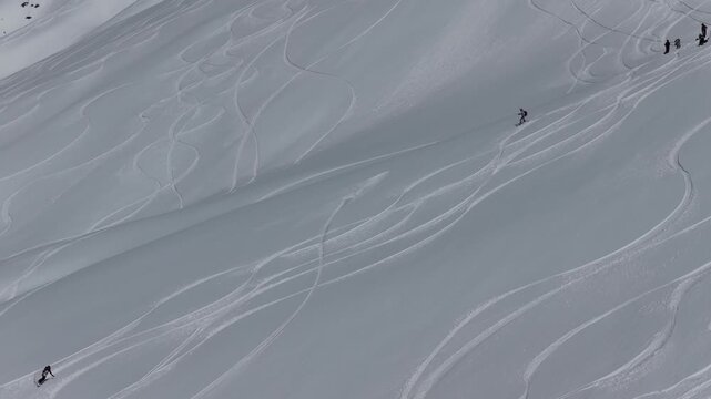 Freeride skiers climbing and descending Bidara peak in Gudauri on deep fresh powder snow, winter adventure in Georgia mountains. Backcountry freeride and skiing untouched powder in snowy mountains.