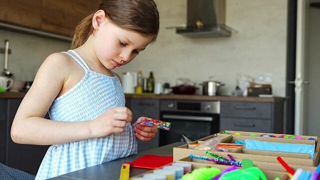 Little girl decorating handmade craft with colorful self adhesive rhinestones at table. Kids creativity fine motor skills development and learning through play concept.