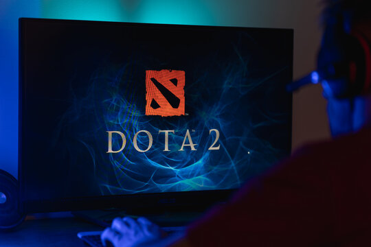 Gamer sitting in front of a computer monitor with the Dota 2 game logo on screen, esports fan ready to play a strategic multiplayer online battle arena MOBA video game.